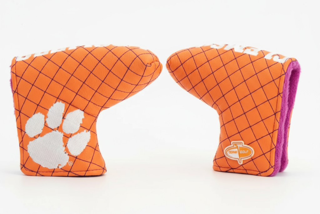 Two orange golf club covers with a grid pattern and paw print design on a white background.