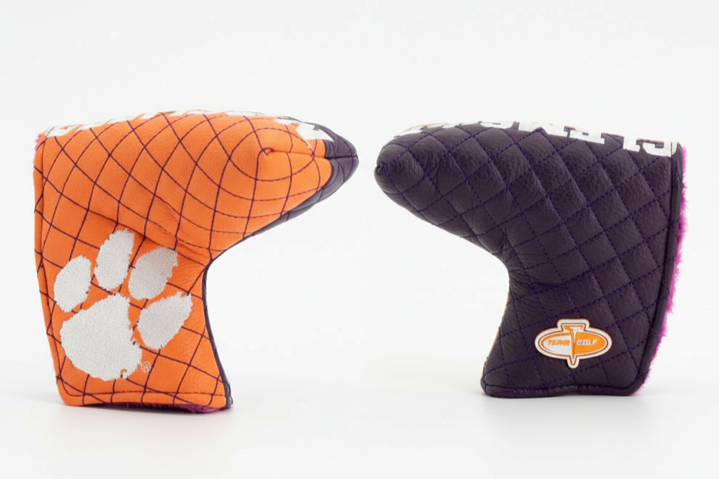 Two golf club covers, one orange with a white paw print and the other black with a logo, on a white background.