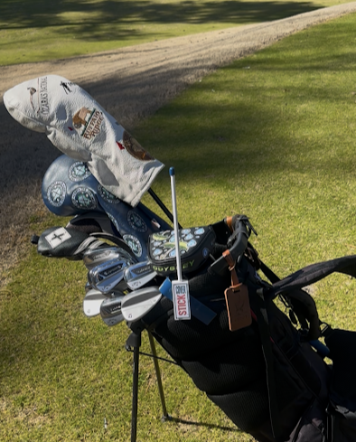 CoverStick rotated upright beside a golf bag, ready to hold a headcover
