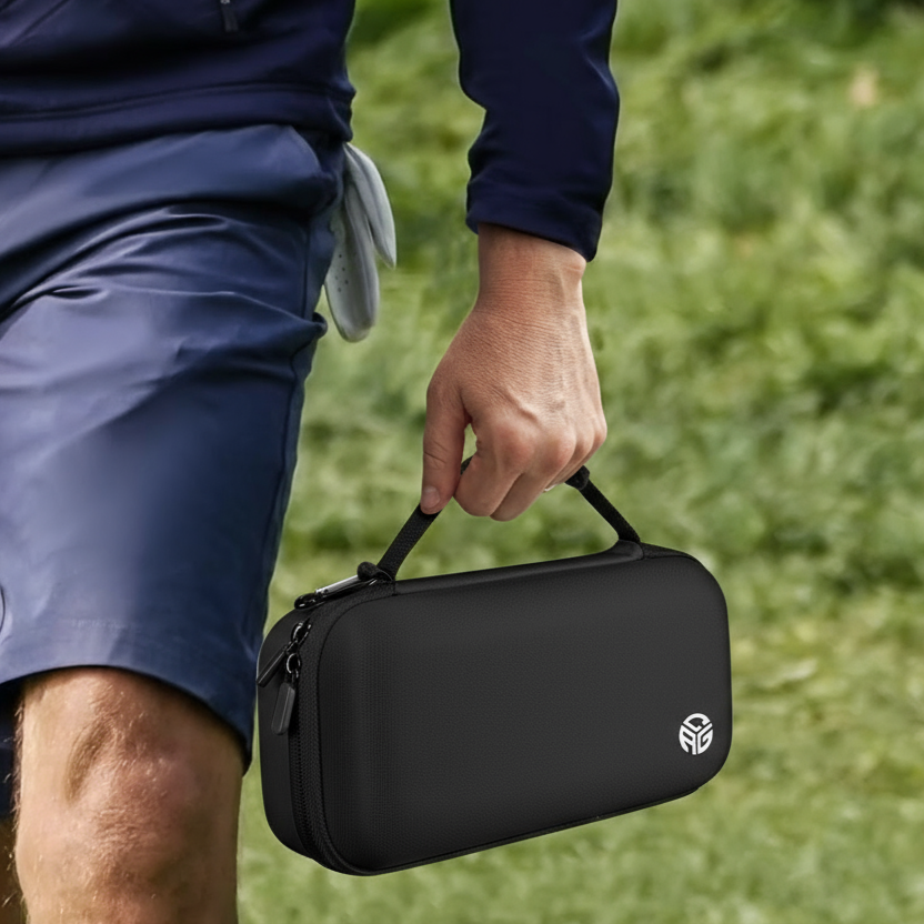 Person holding a black carrying case with a logo on grass
