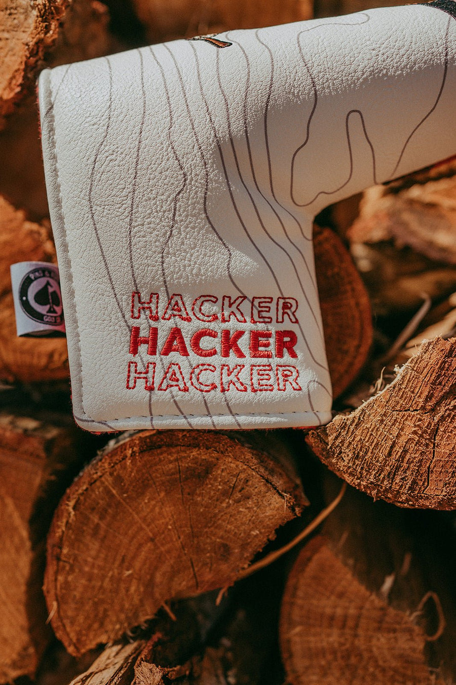 Repeated red and gray Hacker lettering over a pale woodgrain pattern