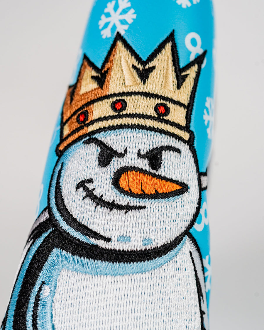 Crowned snowman face with an orange carrot nose on icy blue