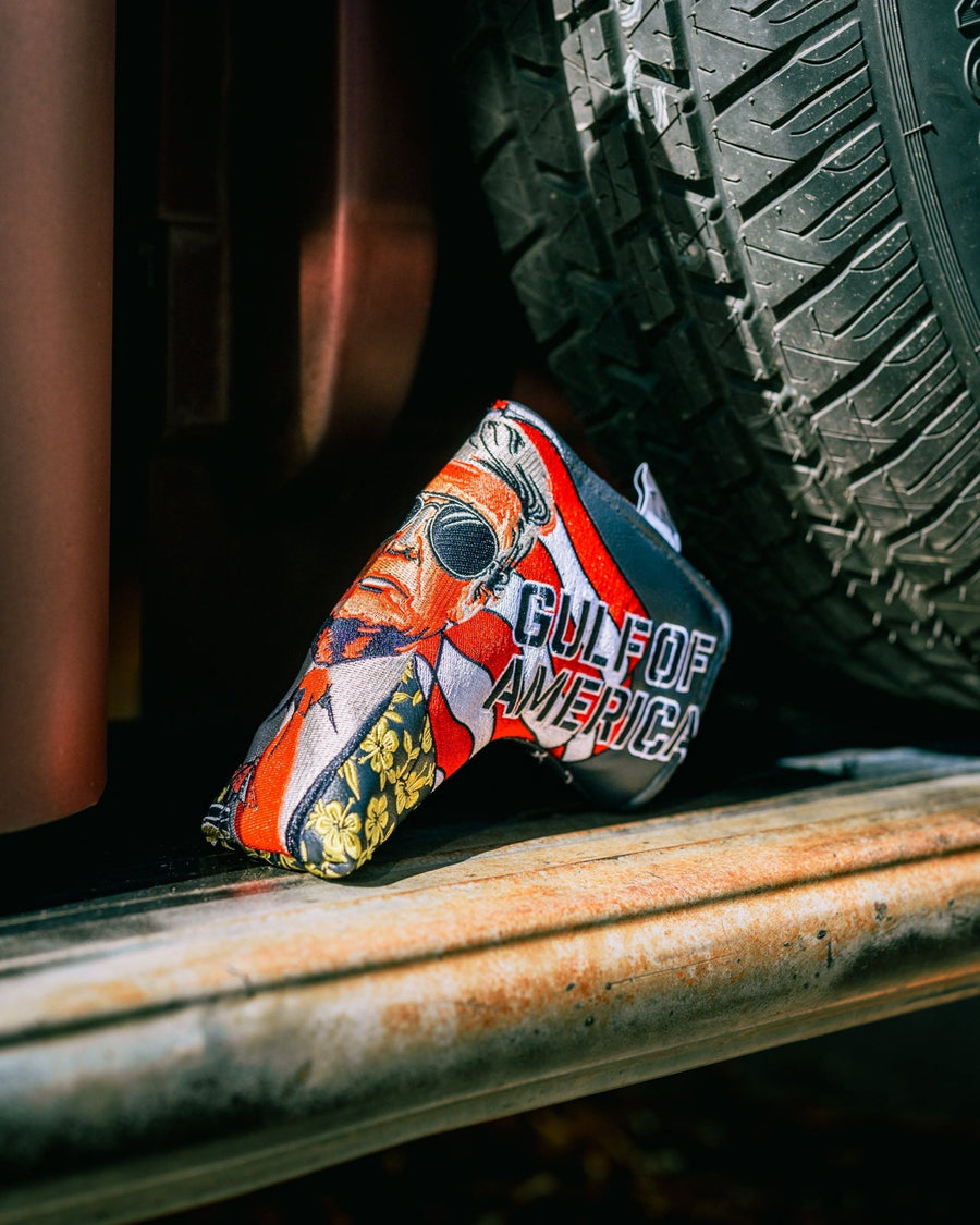 Trump Gulf of America blade cover resting on wood beside a tire