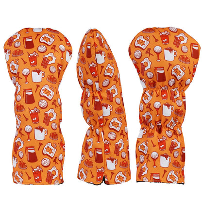 Three golf club heads with orange patterned covers on a white background