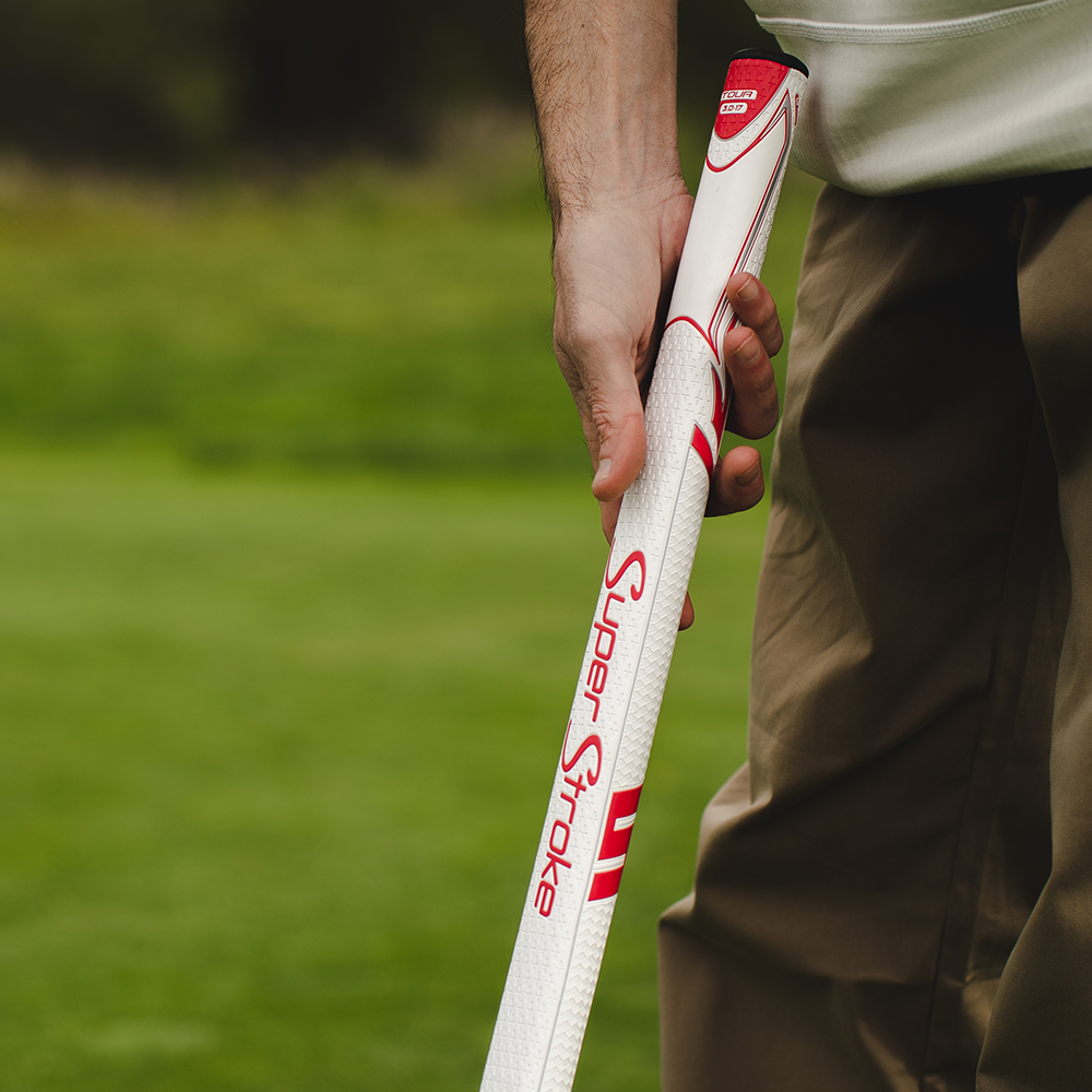 Golfer hält einen verlängerten, weiß-roten SuperStroke Zenergy Tour 3.0 17-Zoll-Griff