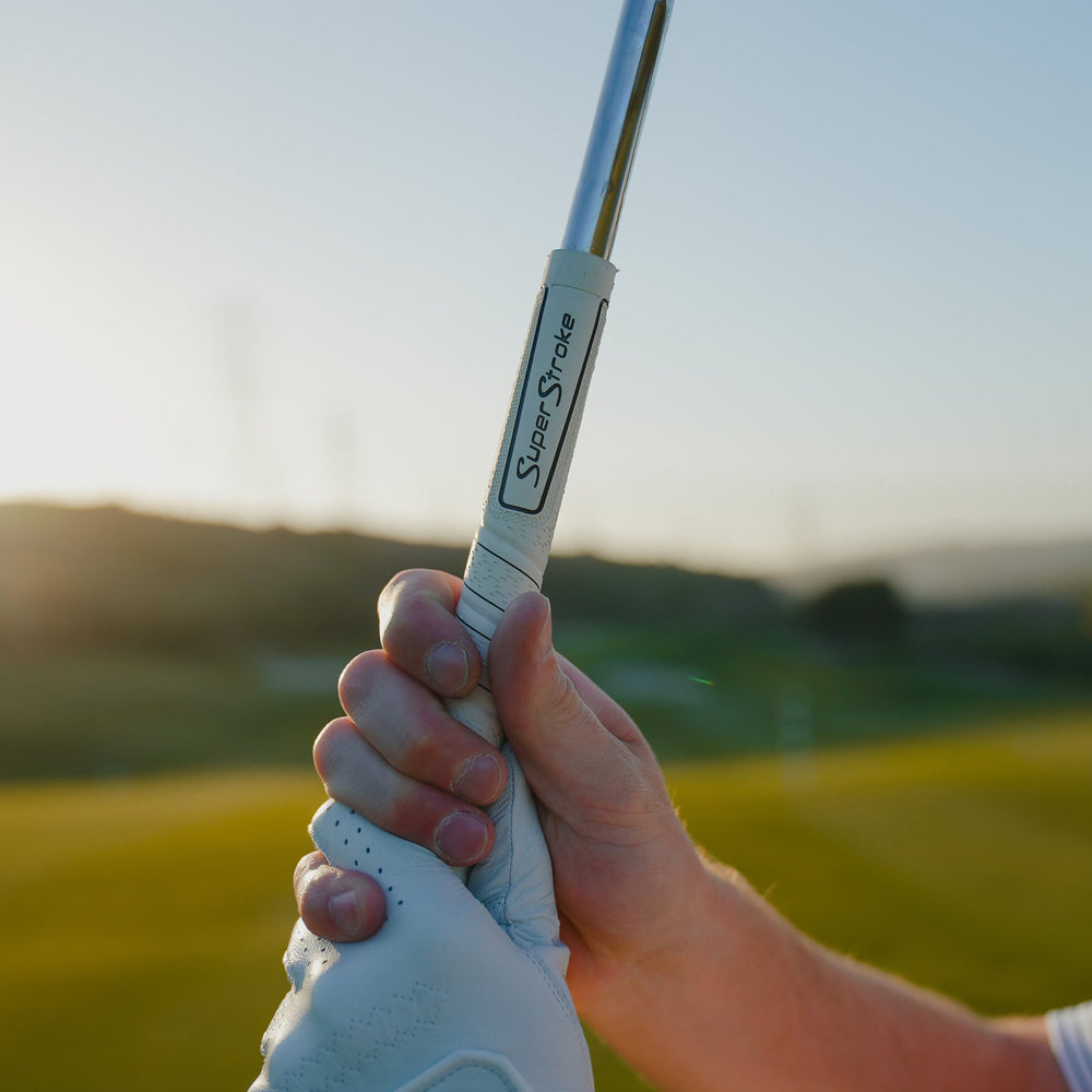 Golfer mit einem weißen SuperStroke REVL Comfort Griff bei Sonnenuntergang