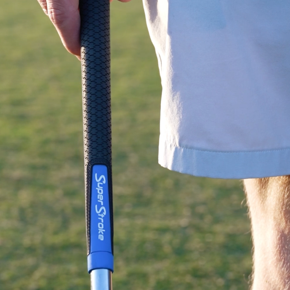 Blau-grauer SuperStroke REVL Player Griff neben einem Golfer gehalten