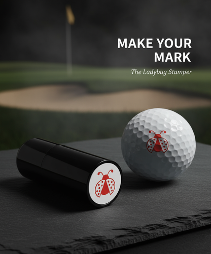 Golf ball and black ladybug stamper on a dark surface with a golf course background.