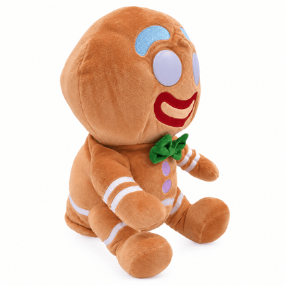 A plush gingerbread man doll sitting upright on a clean white background. The toy features a warm brown body with embroidered details including a green bow tie, purple buttons, white stripes, and a red smile.