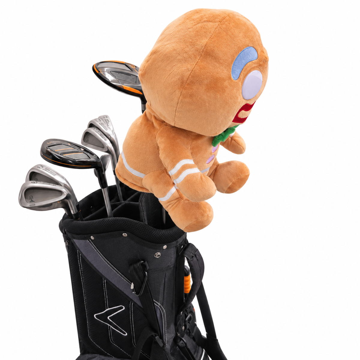 A plush golf toy shaped like a gingerbread person sitting on top of a black golf bag filled with golf clubs, photographed on a clean white background.