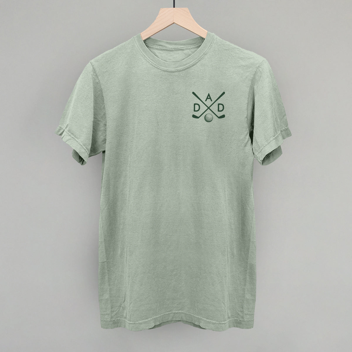 Muted green Golf Dad tee with small crossed-club left-chest graphic