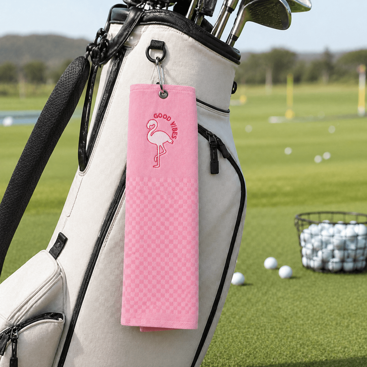 Pink towel with flamingo design hanging on a golf bag on a golf course