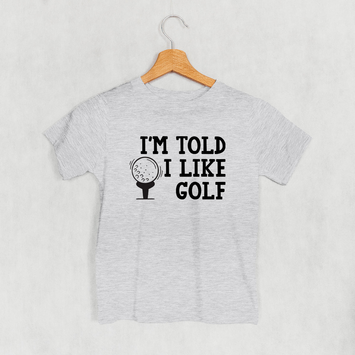 Heather gray I'm Told I Like Golf kids' T-shirt with black lettering and golf-ball graphic