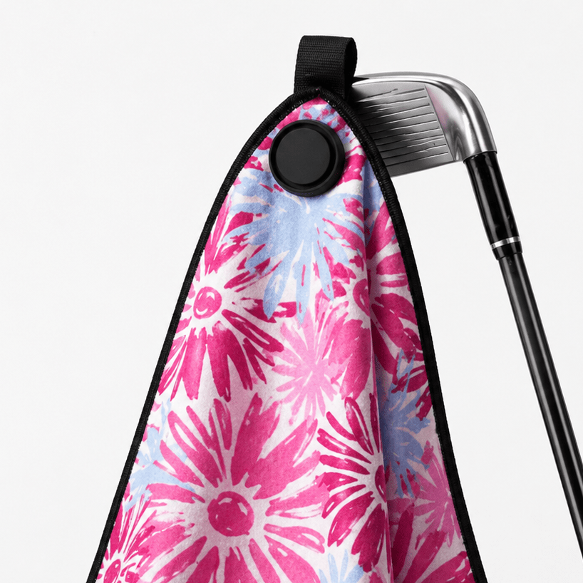 Golf club with a pink floral towel draped over it on a white background