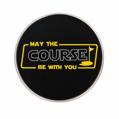 Close-up of black May the Course Be With You golf ball marker with yellow design and white outlined Course lettering