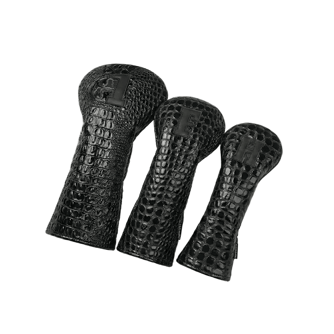 Three black textured golf club head covers on a white background