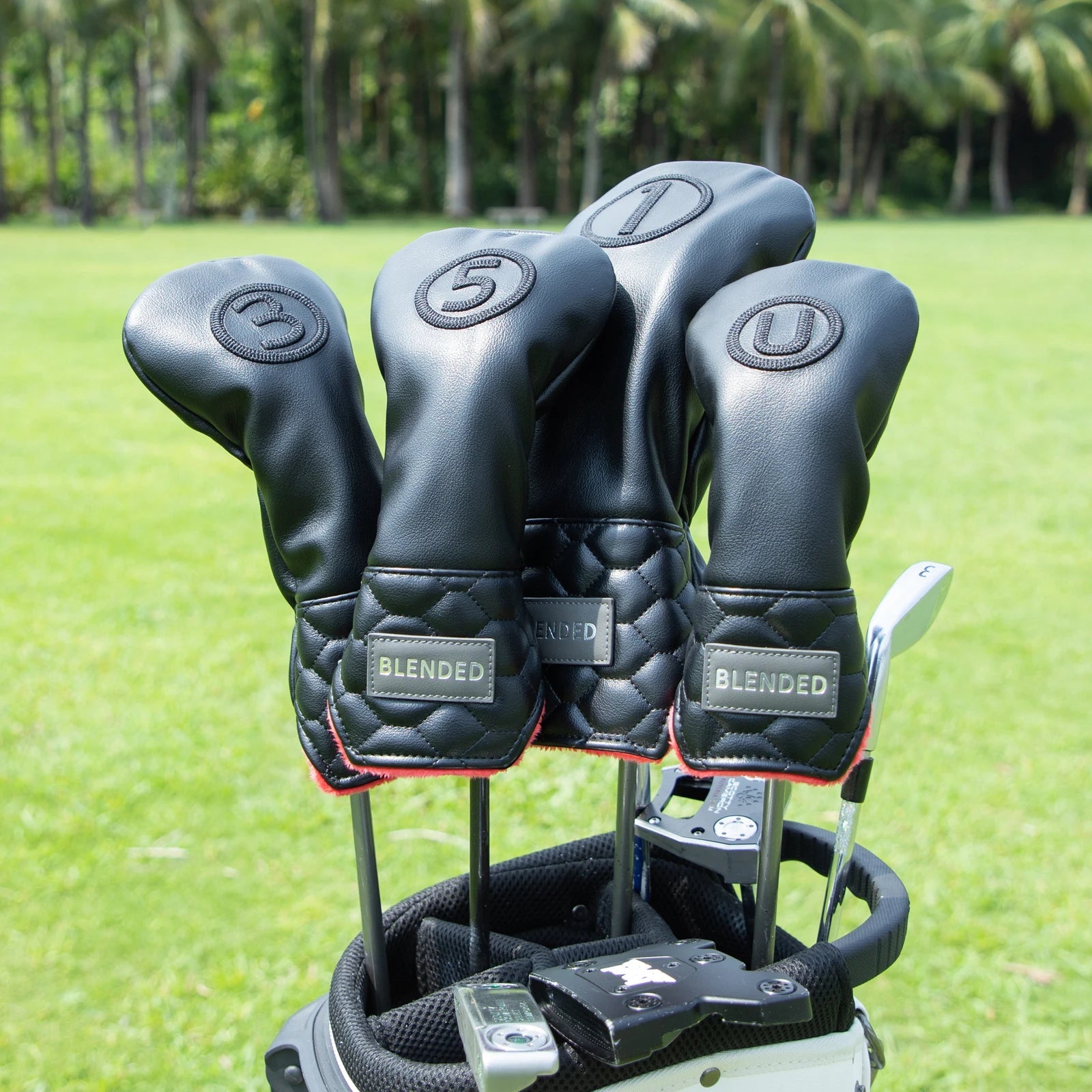 Golf club heads with black covers on a golf bag against a green grass background