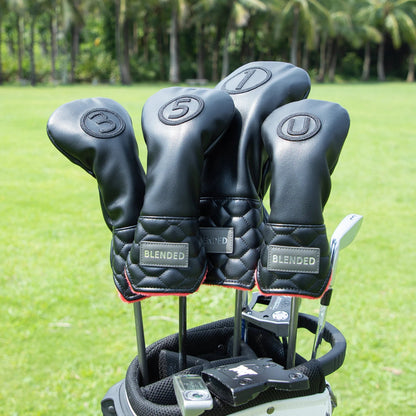 Golf club heads with black covers on a golf bag against a green grass background