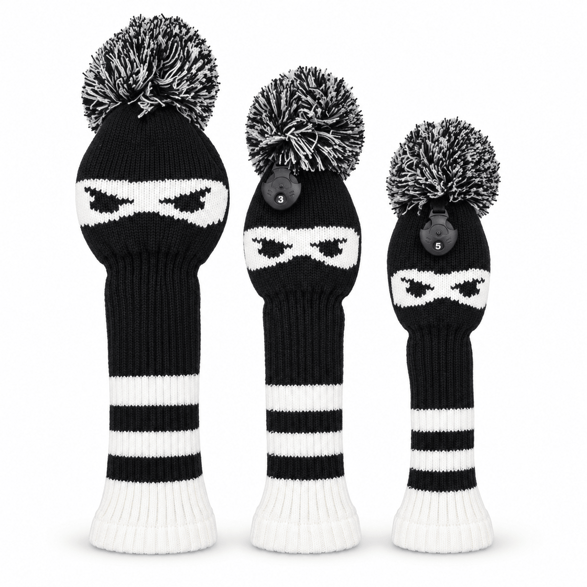 Three black-and-white ninja knit golf headcovers with pom-poms on a white background