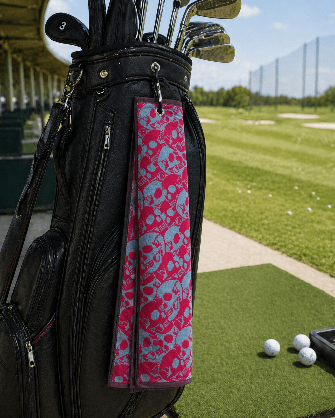 Golf bag with pink and blue skull patterned towel on a golf course