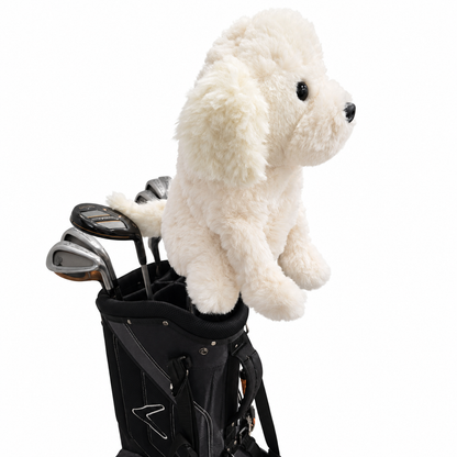 A plush cream-colored dog toy sitting on top of a black golf bag with golf clubs, isolated on a white background.