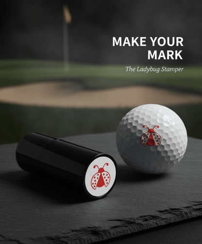 Golf ball and black ladybug stamper on a dark surface with a golf course background.