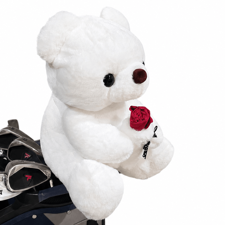White teddy bear holding a red rose on a golf bag with clubs