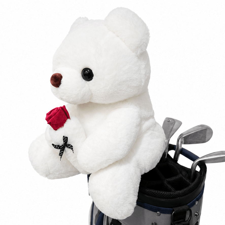 White teddy bear holding a red rose next to a golf bag on a white background