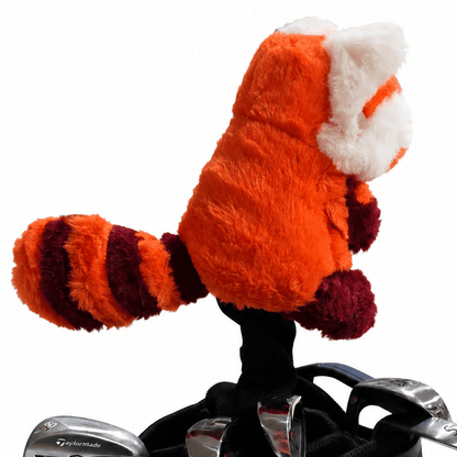 Plush red panda headcover on top of a golf club set with a white background