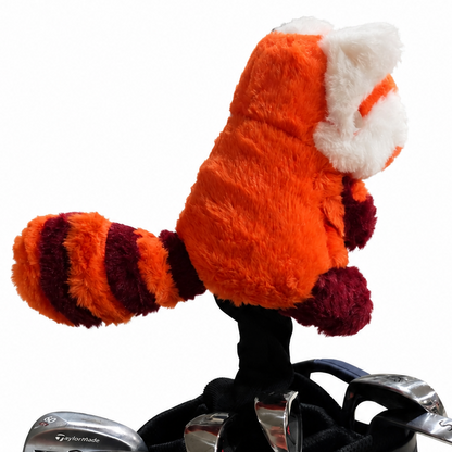 Plush red panda headcover on top of a golf club set with a white background
