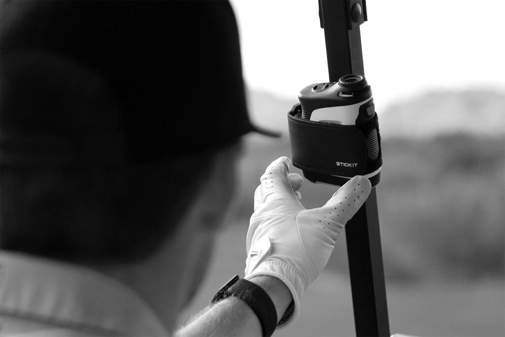 Black STICKIT Gen3 strap holding a rangefinder on a compatible metal cart post; rangefinder not included