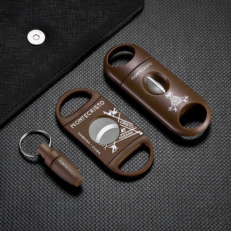 Two brown Montecristo cigar cutters on a textured black surface.