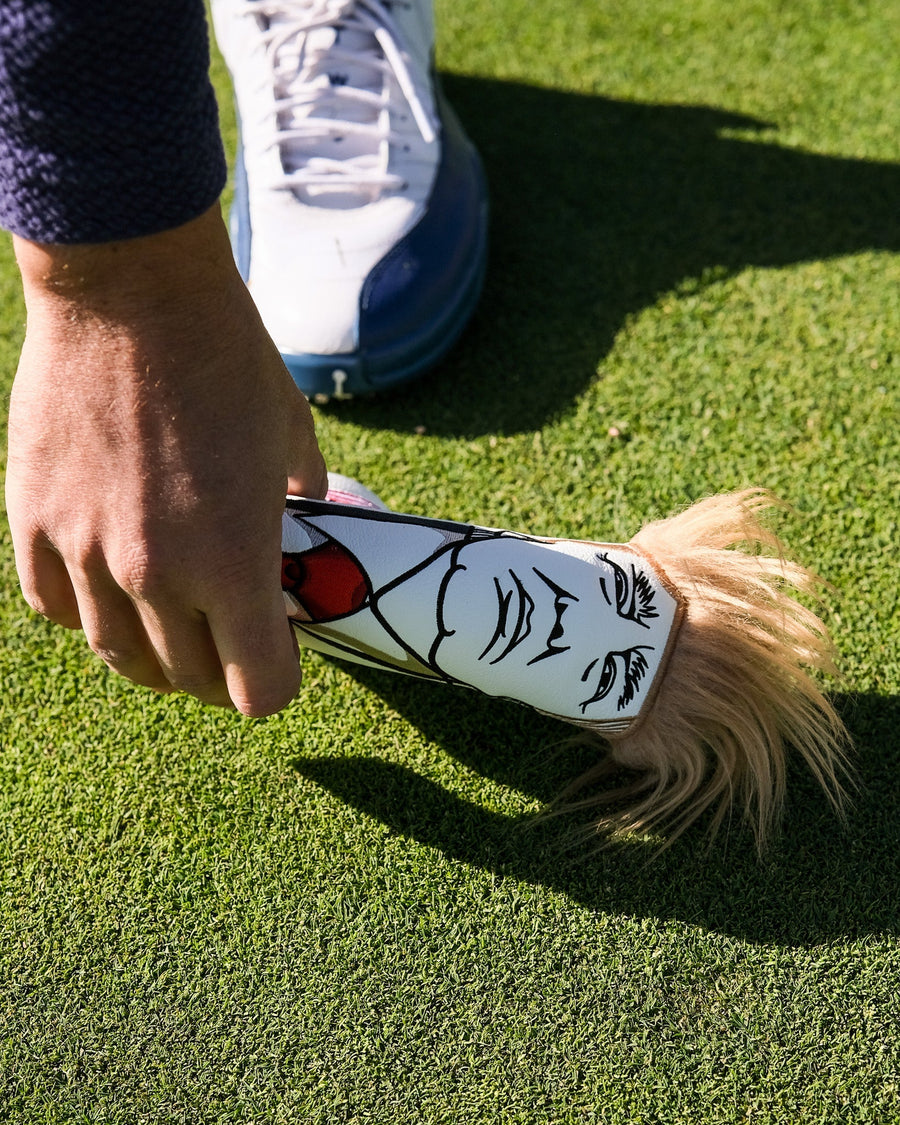 Hand holding the Trump blade cover over green grass